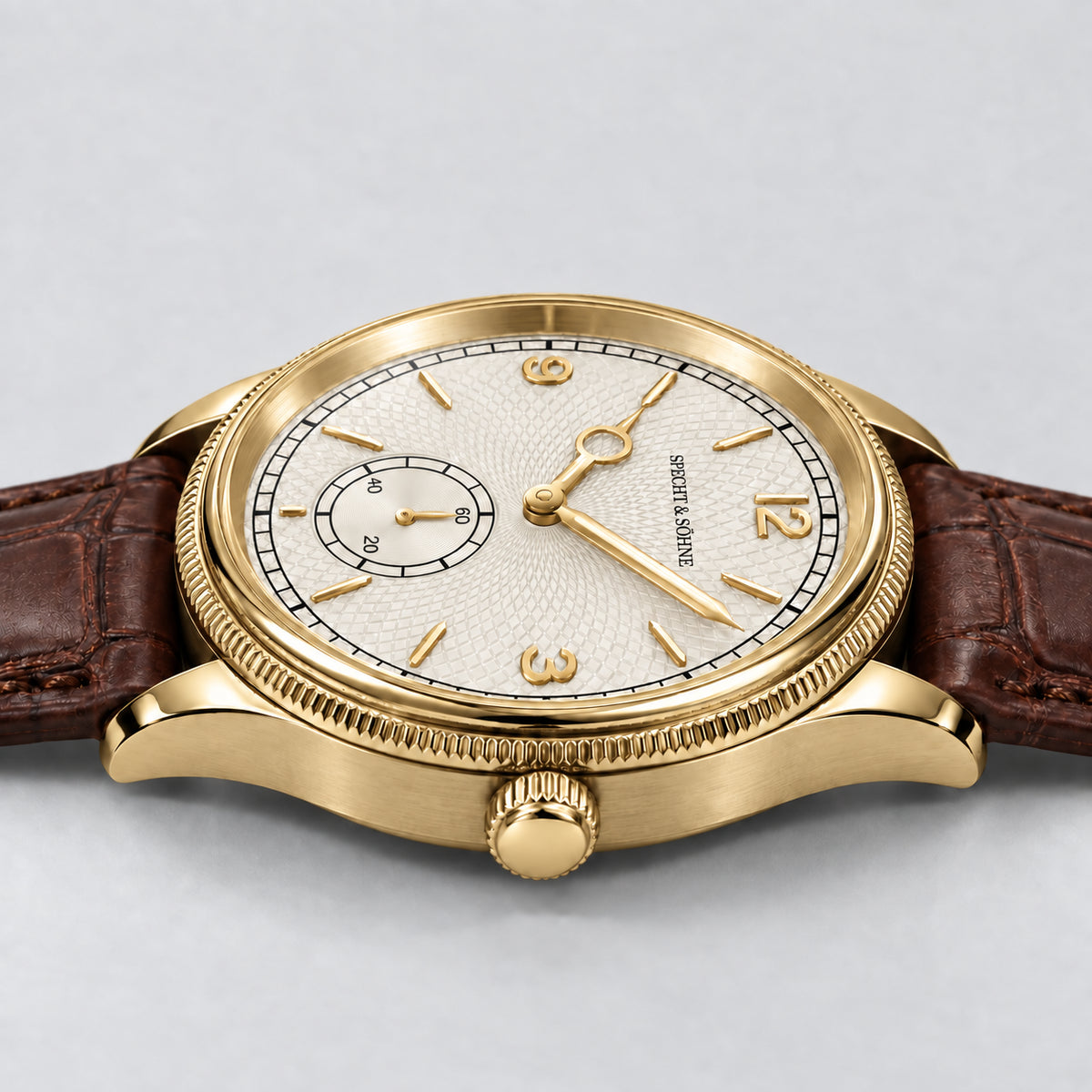 Specht & Söhne Invictus 1986 Gold: vista lateral da caixa e coroa douradas, mostrador branco e pulseira marrom.
