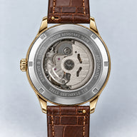 Verso do Specht & Söhne Invictus 1986 Gold, com tampa prateada, movimento visível, laterais e encaixes dourados e pulseira marrom.
