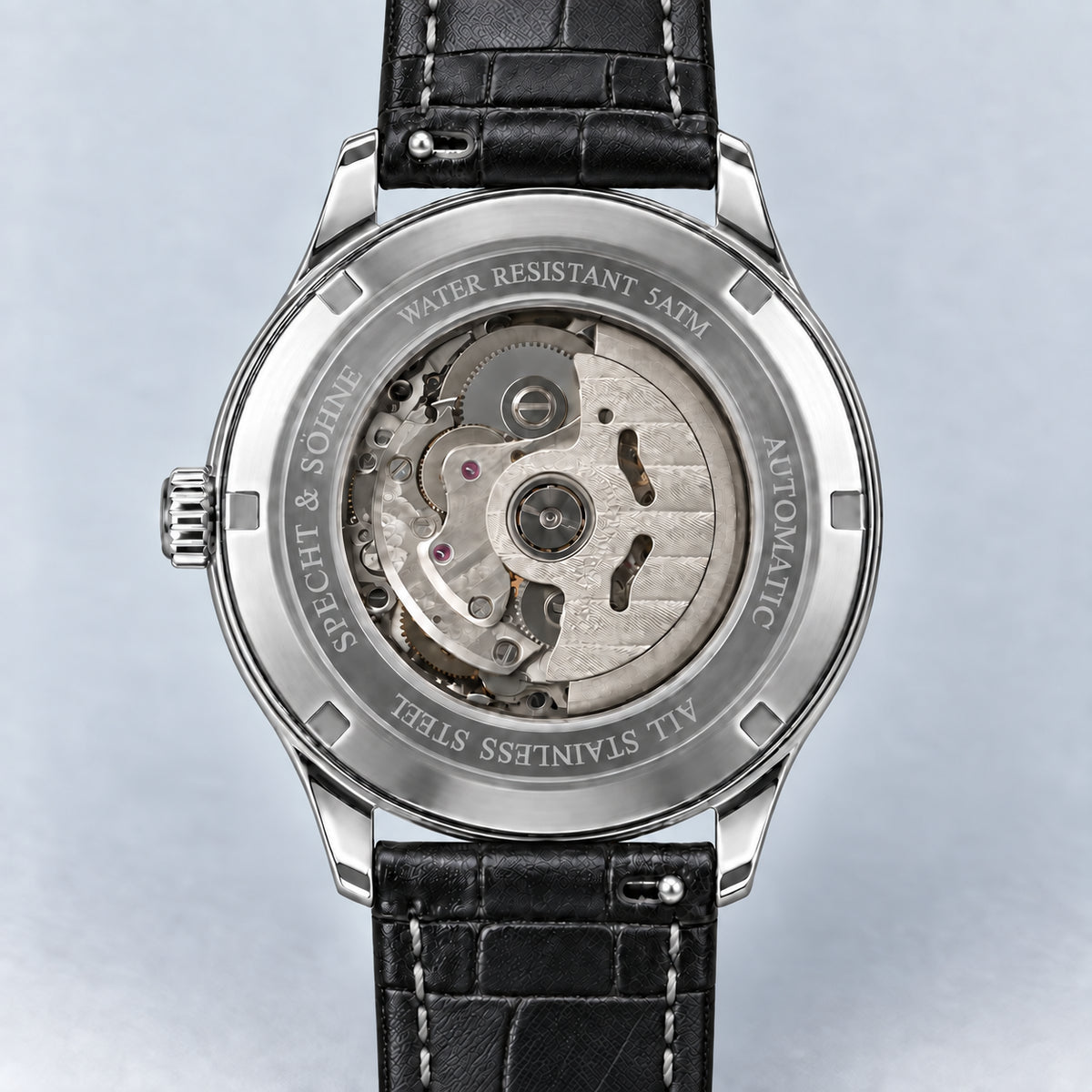 Verso do Specht & Söhne Invictus 1986 White, com tampa prateada, movimento visível, encaixes prateados e pulseira preta.