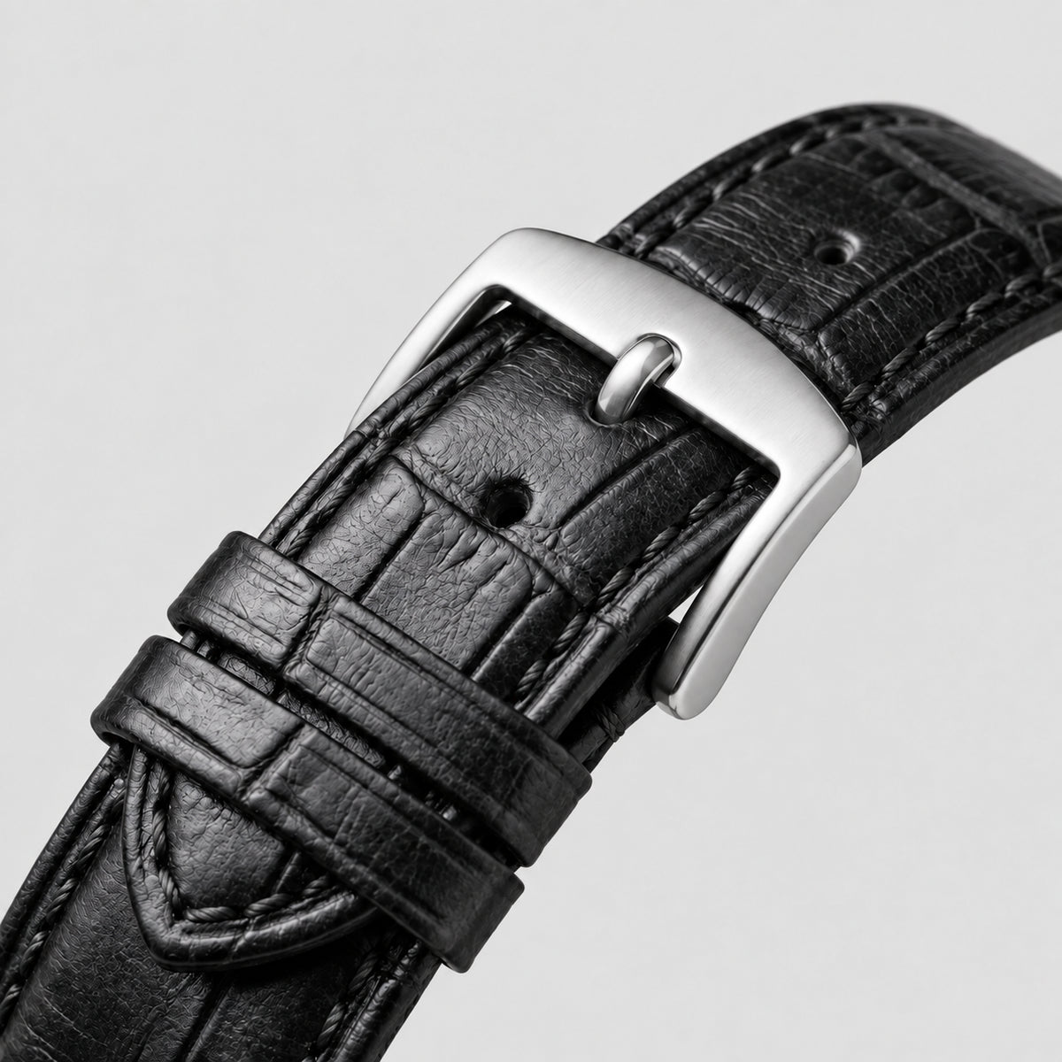 Pulseira preta do Specht & Söhne Invictus 1986 White com textura, costura e fivela de pino prateada sobre fundo claro.