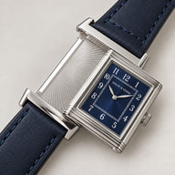 Specht & Söhne Reverso Ultrafino 24mm com caixa reversível aberta, mostrador azul-marinho com numerais arábicos e pulseira de couro azul.
